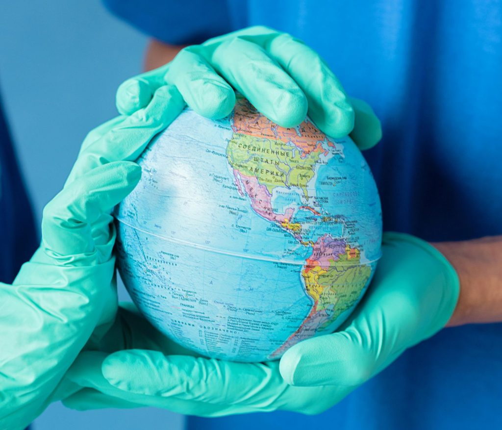 Two people in blue scrubs and gloves holding a globe, symbolizing global health care and environmental protection.